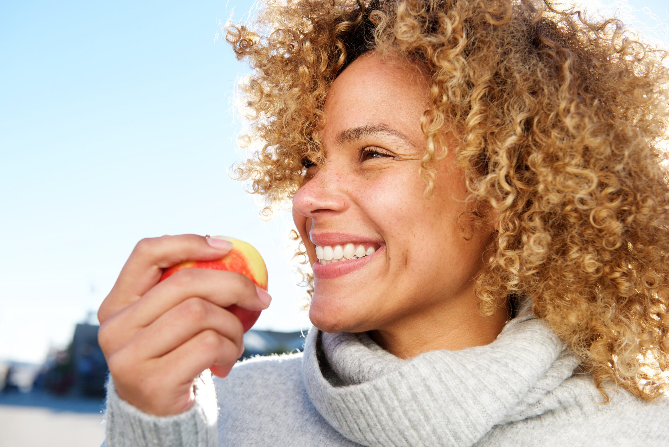 side portrait of healthy young african american woman holding apple